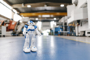 Toy robot standing on floor of factory workshop - KNSF04919