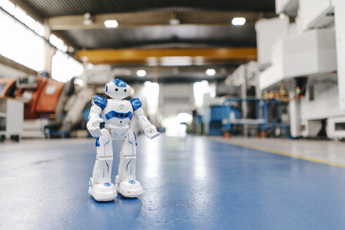 Toy robot standing on floor of factory workshop - KNSF04919