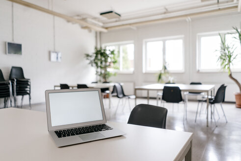 Laptop with blank screen on desk in board room - KNSF04929