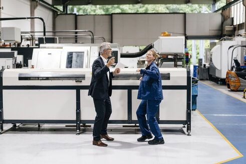 Manager and skilled worker dancing in factory workshop, having fun - KNSF04941