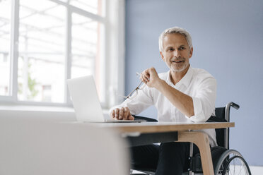 Behinderter Manager im Rollstuhl, der im Büro arbeitet - KNSF04960