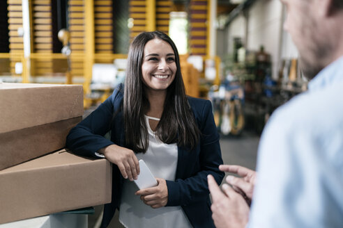 Young woman working in distribution warehouse, talking to colleague - KNSF04963