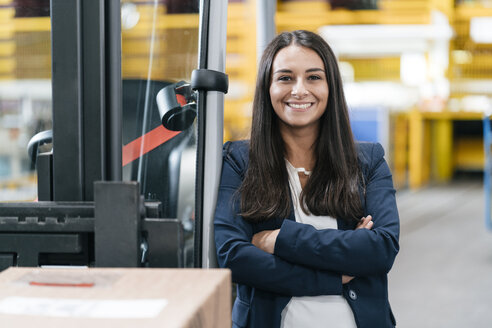 Selbstbewusste Frau im Logistikzentrum, mit verschränkten Armen - KNSF04966