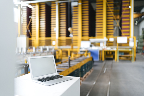 Laptop mit leerem Bildschirm im Logistikzentrum, lizenzfreies Stockfoto