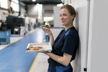 Woman working in high tech company, taking a break, eating pizza - KNSF04989