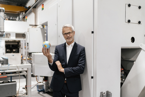 Manager in einem High-Tech-Unternehmen hält lächelnd eine kleine Weltkugel, lizenzfreies Stockfoto