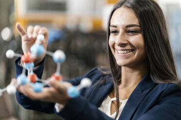 Confident woman working in high tech enterprise, holding molecule model - KNSF04992