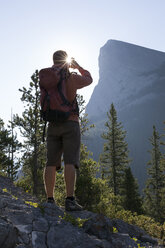 Hiker takes picture with smartphone from mountain ridge, sunrise - AURF06428