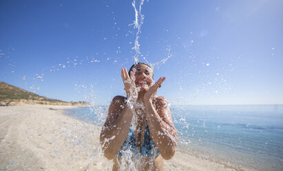 Eine erwachsene Frau wird am Strand vom Wasser umspült - AURF06531