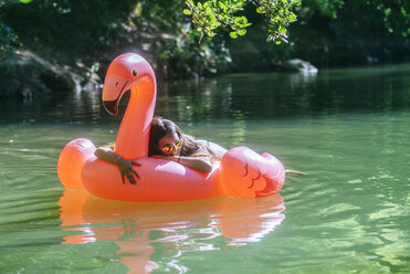 Auf einem aufblasbaren Flamingo auf dem Wasser treibende Frau - KIJF02026