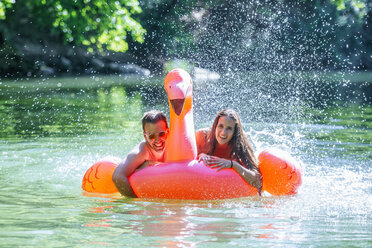 Auf einem aufblasbaren Flamingo auf dem Wasser treibendes Paar - KIJF02027