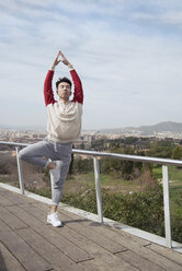Chinesischer Mann beim Yoga in der Vrksasana-Position, Berg Montjuic, Barcelona, Spanien - AURF06765