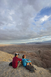 Couple sitting together in badlands section of Anza Borrego State Park and admiring landscape, California, USA - AURF06790