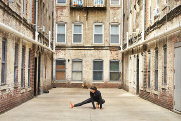 Female runner stretching in urban alley before running, Boston, Massachusetts, USA - AURF06812