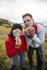 Father and son using lichen to create beards during hiking trip, Merritt, British Columbia, Canada - AURF06836