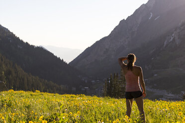 Female trail runner standing while resting in meadow, Alta, Utah, USA - AURF06860