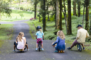 Familie mit Skateboards und Fahrrädern spielt im Park, Bedugul, Bali, Indonesien - AURF06864