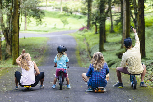 Family with skateboards and bicycles taking selfie in park, Bedugul, Bali, Indonesia - AURF06865
