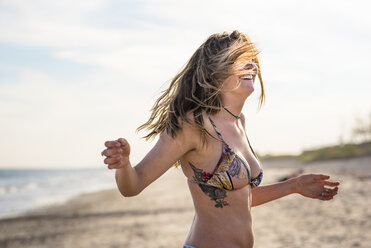 Glückliche Frau im Bikini am Strand - AURF06921