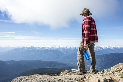 Wanderer ruht sich aus und betrachtet die Aussicht, während er auf dem Gipfel des Whistler Mountain steht, Garibaldi Provincial Park, Whistler, British Columbia, Kanada - AURF06934