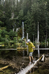 Wanderer balanciert auf einem umgestürzten Baum über einem See, Washington, USA - AURF06971