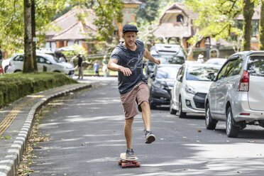 Vorderansicht eines Mannes mit Skateboard auf der Straße, Bedugul, Bali, Indonesien - AURF07034