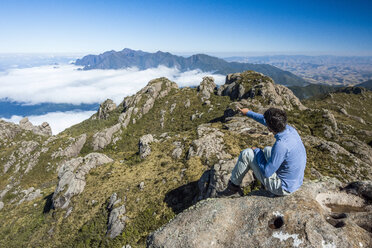 Man sitting on summit of Morro do Couto in Mantiqueira Mountains, Itatiaia National Park, Rio de Janeiro State, Brazil - AURF07067