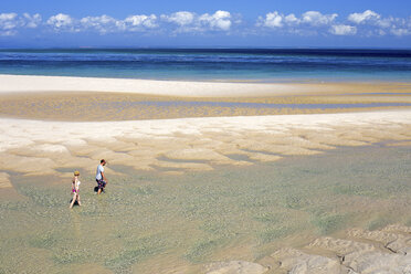 Man and woman walking together along sandy coastal beach of Benguerra island, Mozambique - AURF07078