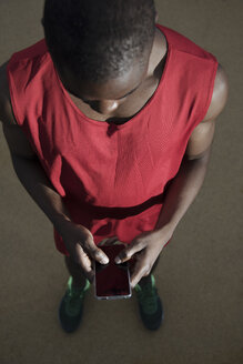 Männlicher Sportler, der im Freien steht und sein Smartphone benutzt, Barcelona, Spanien - AURF07114