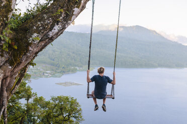 Man sitting on swing against Lake Buyan, Bedugul, Bali, Indonesia - AURF07134