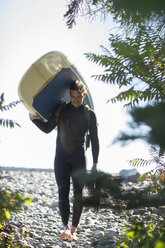 Mann mit Stand Up Paddleboard am felsigen Strand - AURF07150