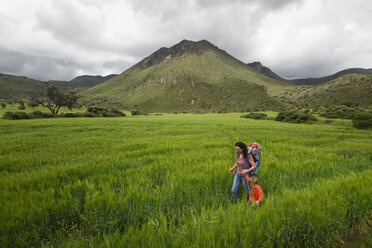 Mother with son hiking through field at archeological area of Xihuingo, Tepeapulco, Hidalgo, Mexico - AURF07162