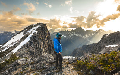 Mountain climber looking at view in North Cascade Mountain Range at sunset, Chilliwack, British Columbia, Canada - AURF07179