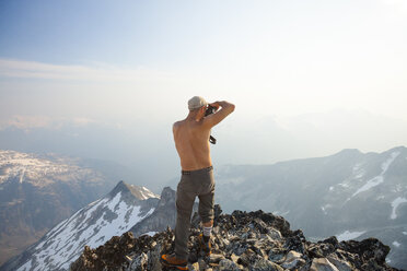 Mountain climber taking photo from summit of Ashlu Mountain in Coast Mountain Range, Squamish, British Columbia, Canada - AURF07186