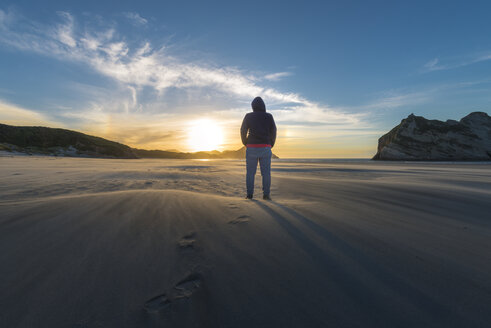 Neuseeland, Südinsel, Puponga, Wharariki Beach, Frau am Strand bei Sonnenuntergang - MKFF00430