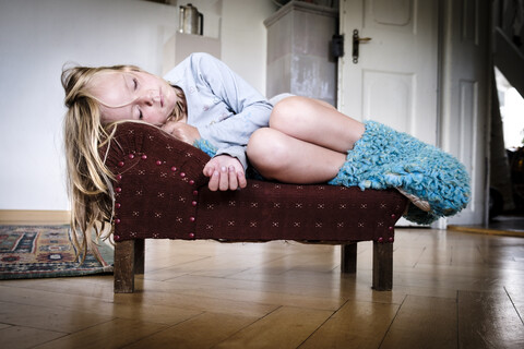 Little girl sleeping on a tiny vintage sofa stock photo