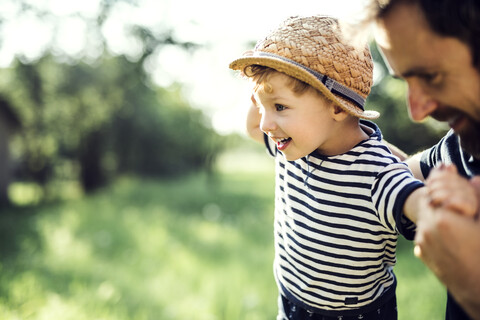 Vater, der einem kleinen Jungen beim Balancieren im Freien hilft, lizenzfreies Stockfoto