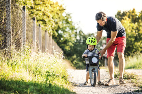 Vater unterrichtet kleinen Sohn beim Fahrradfahren - HAPF02734
