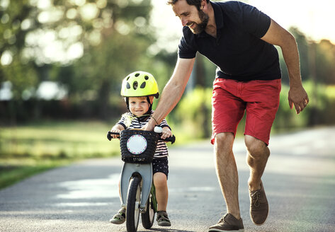 Vater unterrichtet kleinen Sohn beim Fahrradfahren - HAPF02736