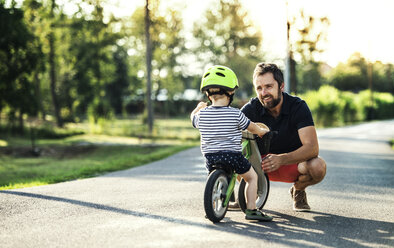 Vater unterstützt kleinen Sohn auf dem Fahrrad - HAPF02739