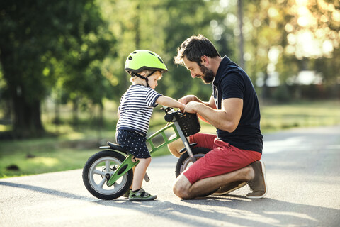 Vater unterstützt kleinen Sohn auf dem Fahrrad, lizenzfreies Stockfoto