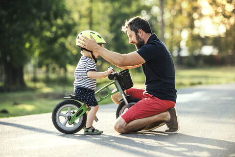 Vater unterstützt kleinen Sohn auf dem Fahrrad, lizenzfreies Stockfoto