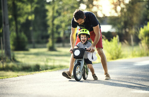 Vater unterrichtet kleinen Sohn beim Fahrradfahren - HAPF02743