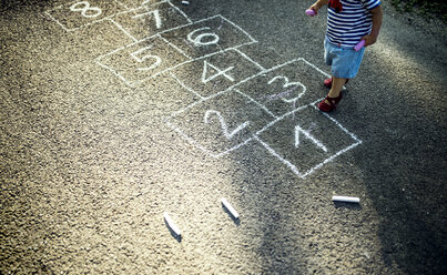 Little girl with drawn hopscotch on the street, partial view - HAPF02746