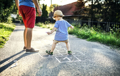 Mature man playing hopscotch together with his little son - HAPF02748