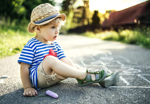 Tagträumendes Kleinkind auf der Straße sitzend, lizenzfreies Stockfoto