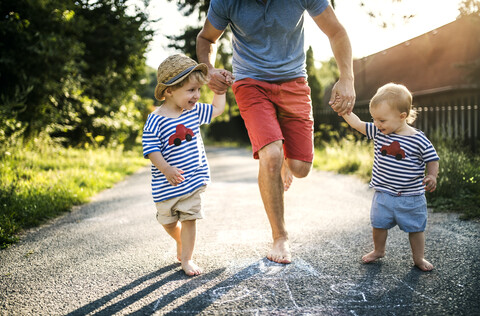 Mature man playing hopscotch together with his little children stock photo