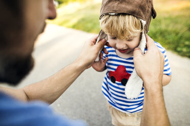 Father putting on pilot hat for his little son - HAPF02777