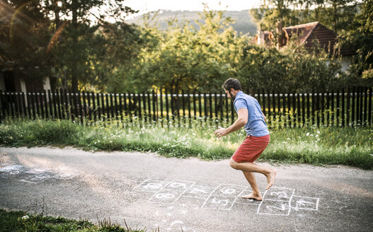 Man playing hopscotch with naked feet - HAPF02786