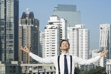 Happy and content successful business man on city rooftop - SBOF01538